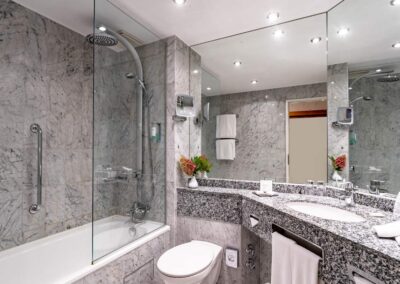 Modernes Badezimmer mit bodengleicher Dusche, Waschbecken und großem Spiegel.