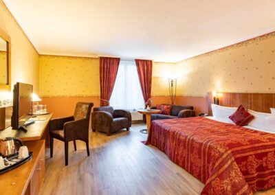 Gemütliches Hotelzimmer mit Doppelbett, warmer Beleuchtung und Holzmöbeln.