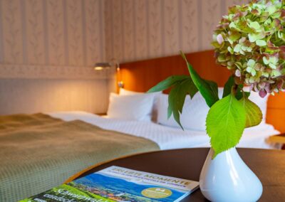 Nahaufnahme eines Nachttischs mit Vase, frischen Blumen und einem Buch.