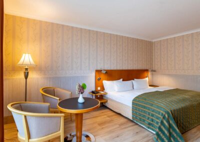Hotelzimmer mit Doppelbett, Holzdekor und Mustertapete.