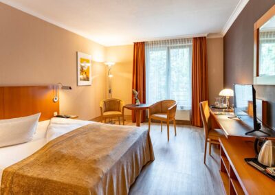 Helles Zimmer mit Doppelbett, Schreibtisch und Wandbeleuchtung