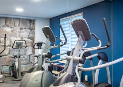 Fitnessraum mit Trainingsgeräten und Wandspiegeln.
