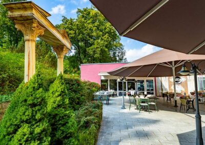 Außenansicht des Hotels mit Garten, Sitzgelegenheiten und grünem Bewuchs.