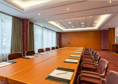 Tagungsraum mit großem Konferenztisch, Stühlen und Beamer.