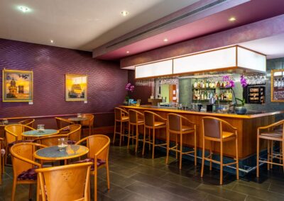 Hotelbar mit Theke, Barhockern und Regal mit Getränken im Hintergrund.